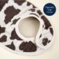 Cow print bib with adjustable snap closure.
