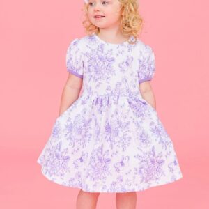 Child in floral dress and white bow smiling.