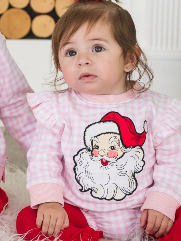 rufflebutts pink gingham santa applique romper Child in Santa-themed pajamas sitting indoors.
