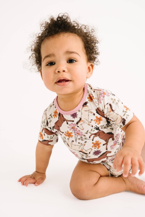 little one shop prairie ponies bamboo shorts set Baby in floral horse-patterned onesie crawling.