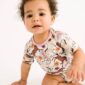 Baby in floral horse-patterned onesie crawling.