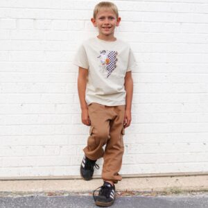 Smiling child in patterned shirt and tan pants.