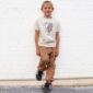 Smiling child in patterned shirt and tan pants.