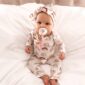 Baby in rainbow pajamas with pacifier on bed.