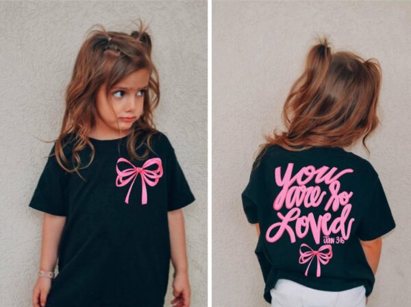 Girl wearing T-shirt with bow and motivational text.