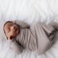 Sleeping newborn baby in gray outfit on bed.