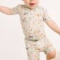 Baby wearing farm-themed outfit, standing on one leg.