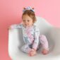 Baby on chair in bow-patterned onesie.