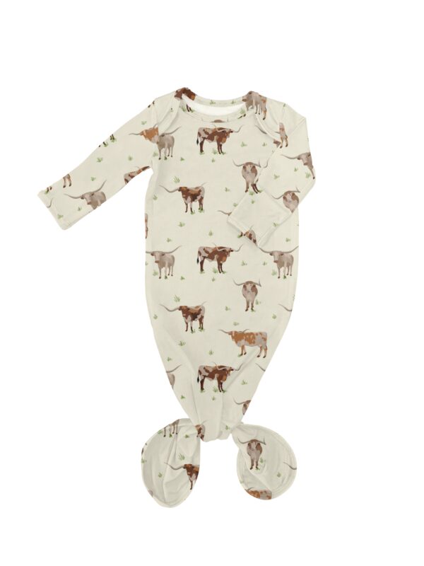 Infant gown with cow pattern on white background.