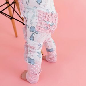 Baby wearing cute ruffled leggings on pink background.