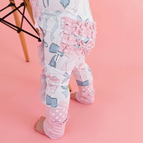 gigi and max samantha bows ruffle zip bamboo sleeplies little outfit Baby wearing cute ruffled leggings on pink background.