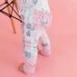 Baby wearing cute ruffled leggings on pink background.
