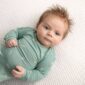 Baby in green outfit lying on blanket