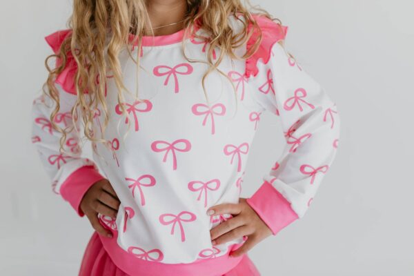 product Child wearing pink bow-patterned sweater.