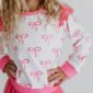 Child wearing pink bow-patterned sweater.