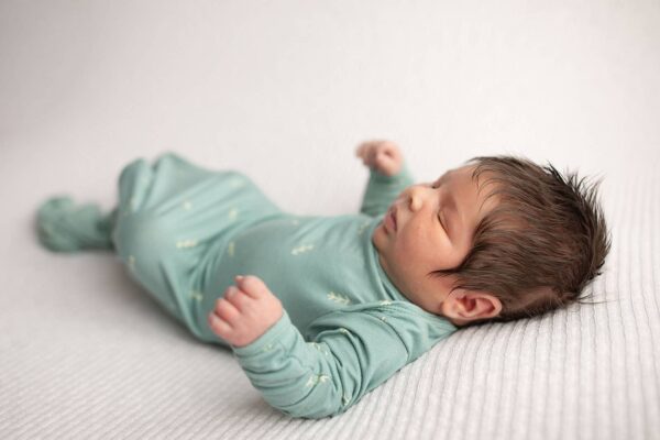 three little tots arrow print knotted newborn baby gown pajamas Newborn baby in green outfit sleeping peacefully.