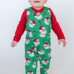 Child in Christmas-themed pajamas smiles.