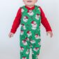 Child in Christmas-themed pajamas smiles.