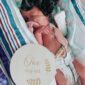 Newborn baby with one day old sign.