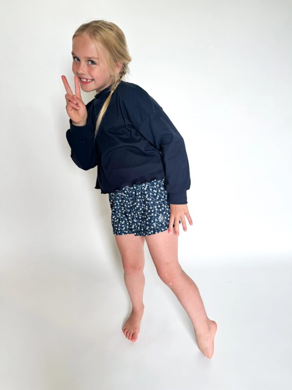 Child posing with peace sign and smile.