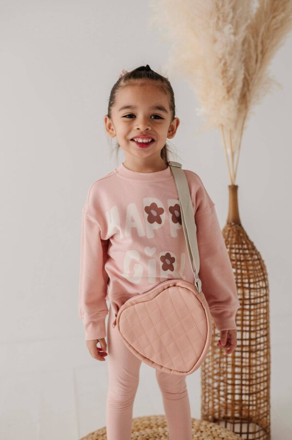 babysprouts clothing company boxy sweatshirt bamboo Smiling child in pink outfit with heart purse.