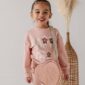 Smiling child in pink outfit with heart purse.