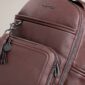 Brown textured backpack with zippers and tassel detail.