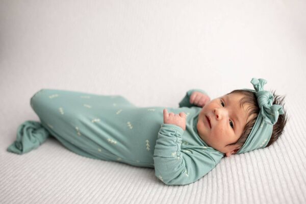 three little tots arrow print knotted newborn baby gown pajamas Baby in teal outfit lying on white blanket.