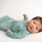 Newborn baby in green onesie lying down