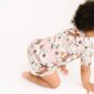 Baby crawling in floral romper, white background.
