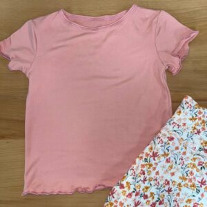 Pink shirt with floral skirt on wooden surface.