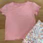 Pink shirt with floral skirt on wooden surface.