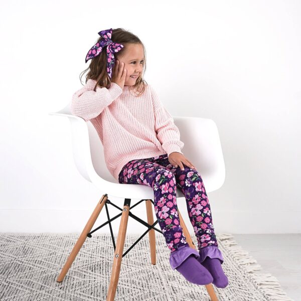 gigi and max mila leggings and sweater set Smiling girl in floral leggings sitting on chair.