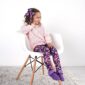 Smiling girl in floral leggings sitting on chair.