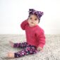 Baby in pink sweater with floral headband.
