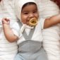 Smiling baby with pacifier in cozy outfit.