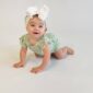 Baby crawling with white bow and floral romper.