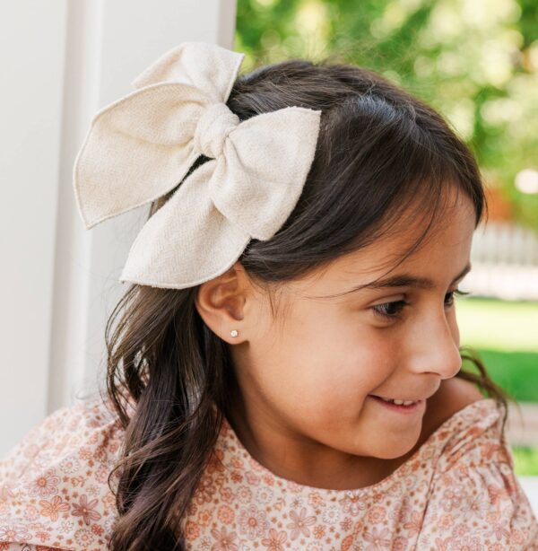 cherished moments kids 14k gold clear cz earrings Child with large bow in hair, smiling