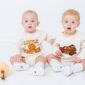 Two babies in cute fall-themed outfits