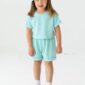 Smiling child in teal outfit and bow