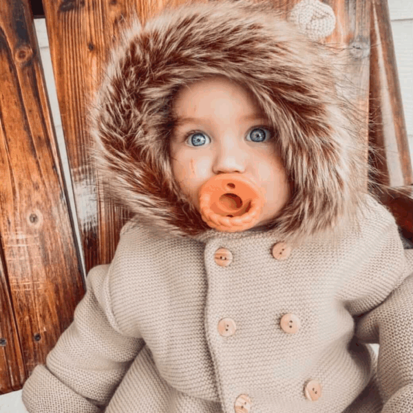 itzy ritzy sweetie soother™ pacifier sets (2 pack): agave + succulent cables Baby with pacifier in winter coat.
