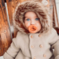 Baby with pacifier in winter coat.
