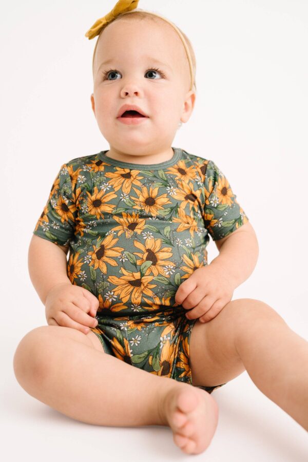 little one shop sunflower meadow bamboo shorts set Baby wearing sunflower-patterned outfit, yellow bow.