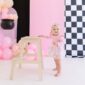 Baby in pink dress with balloons and step stool.