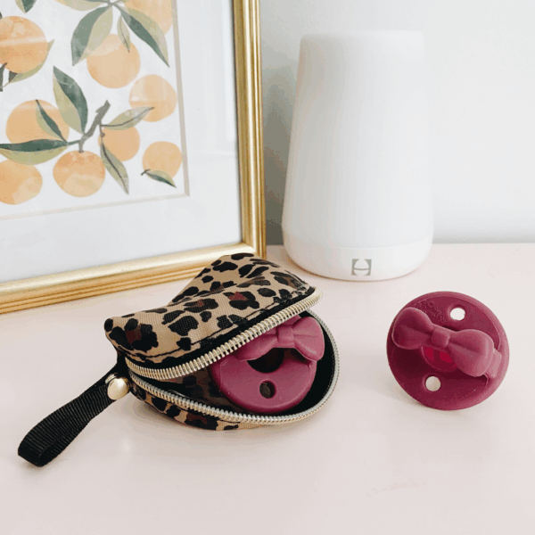 itzy ritzy sweetie soother™ pacifier sets (2 pack): agave + succulent cables Leopard case and pink pacifiers on shelf.