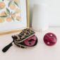Leopard case and pink pacifiers on shelf.