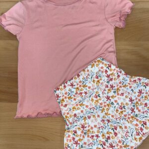Pink shirt and floral skirt set on wood floor.