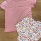 Pink shirt and floral skirt set on wood floor.