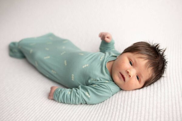 three little tots arrow print knotted newborn baby gown pajamas Newborn baby in green outfit on white blanket.