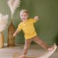 Child balancing on wooden board in striped shirt.